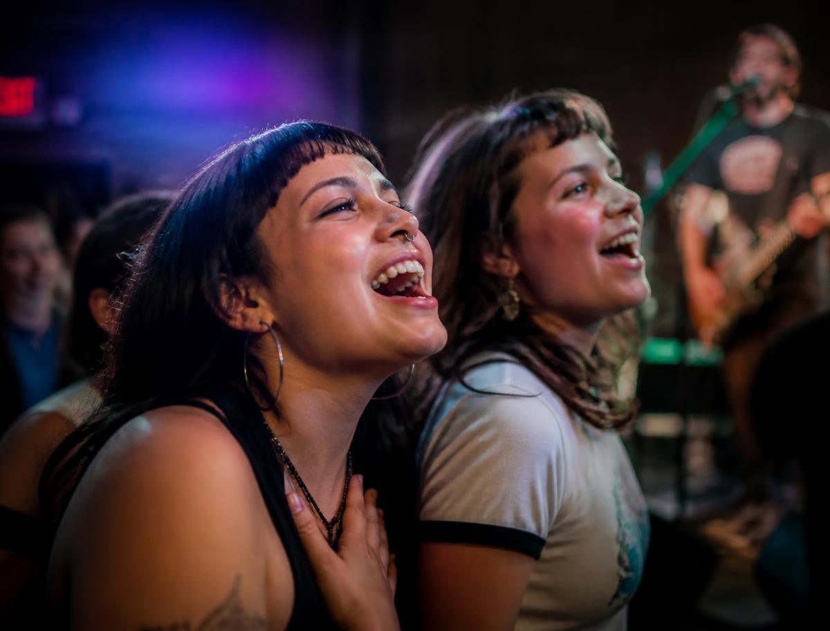 Two fans singing along at an intimate venue